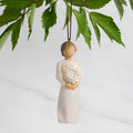Front view: Dated Ornament of figure holding pierced gold-leaf wreath of hearts. 2024 written on wreath; loop and hook in head