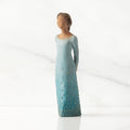 Front/left view: Darker-skin figure, arms clasped behind back, hair and deep blue ombré garment dotted with gold leaf
