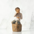 Front view: Figure of lighter-skin child, kneeling on rock, holding wire circle with ‘love you’ written in wire