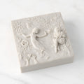 Closed white resin box; lid carved with figural and organic imagery