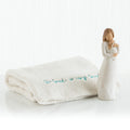 Brown haired woman figurine wearing white holding baby - next to white towel