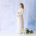 Willow Tree Cherish, 8.5”h hand-painted standing pregnant resin figure in cream dress, both hands on belly, in front of light blue painting
