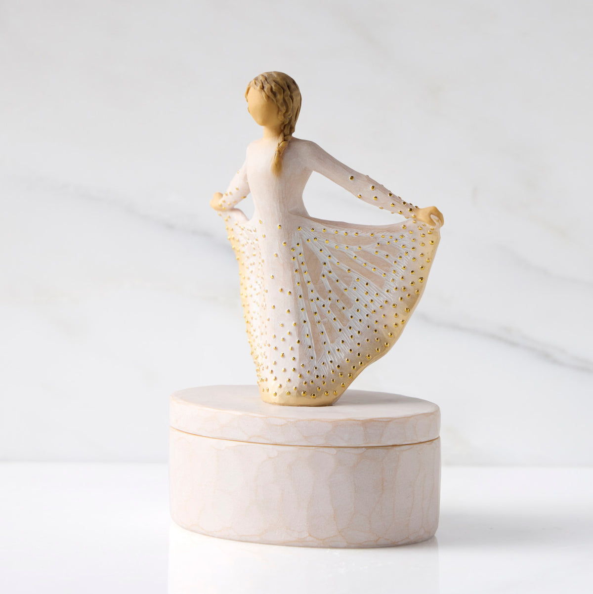 Left view: oval resin box, with 3-D figure atop lid, in cream and gold carved dress