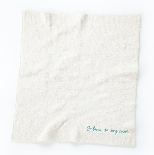 Overview of white towel with 'so loved, so very loved' in light blue in the right corner