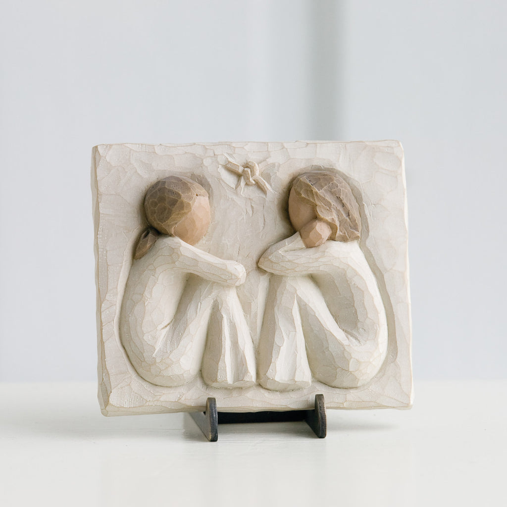 Small cream rectangle plaque with two girl figurines carved in sitting down facing one another
