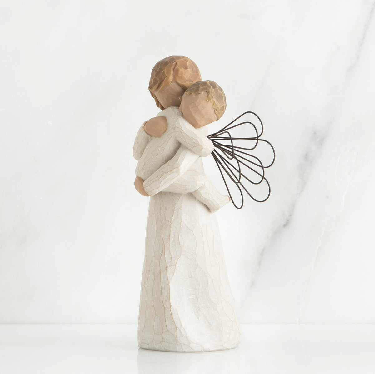 Angel figurine with black wire wings  in white holding baby in her arms