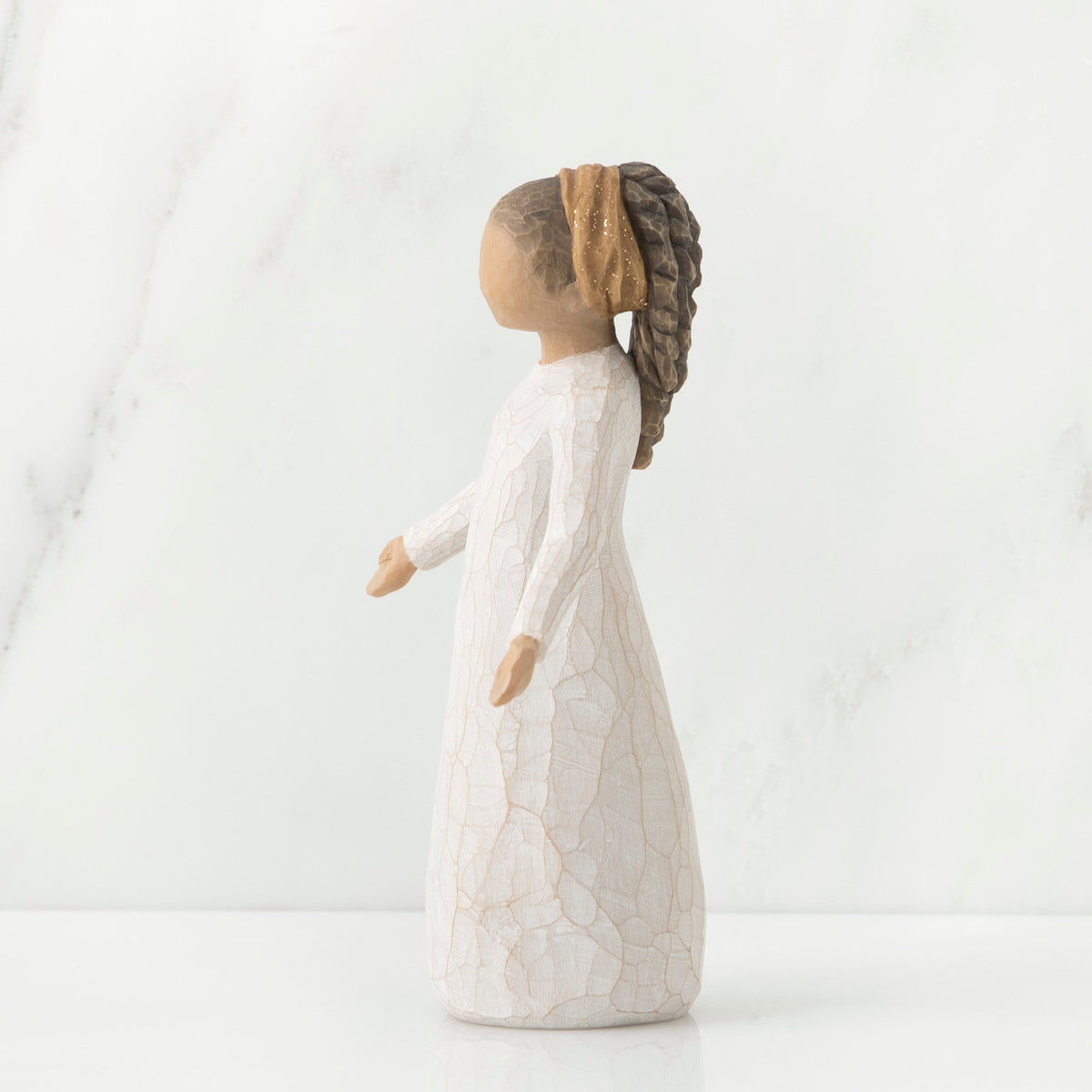 Side view of brunette girl figurine with braided ponytail wearing white dress standing up
