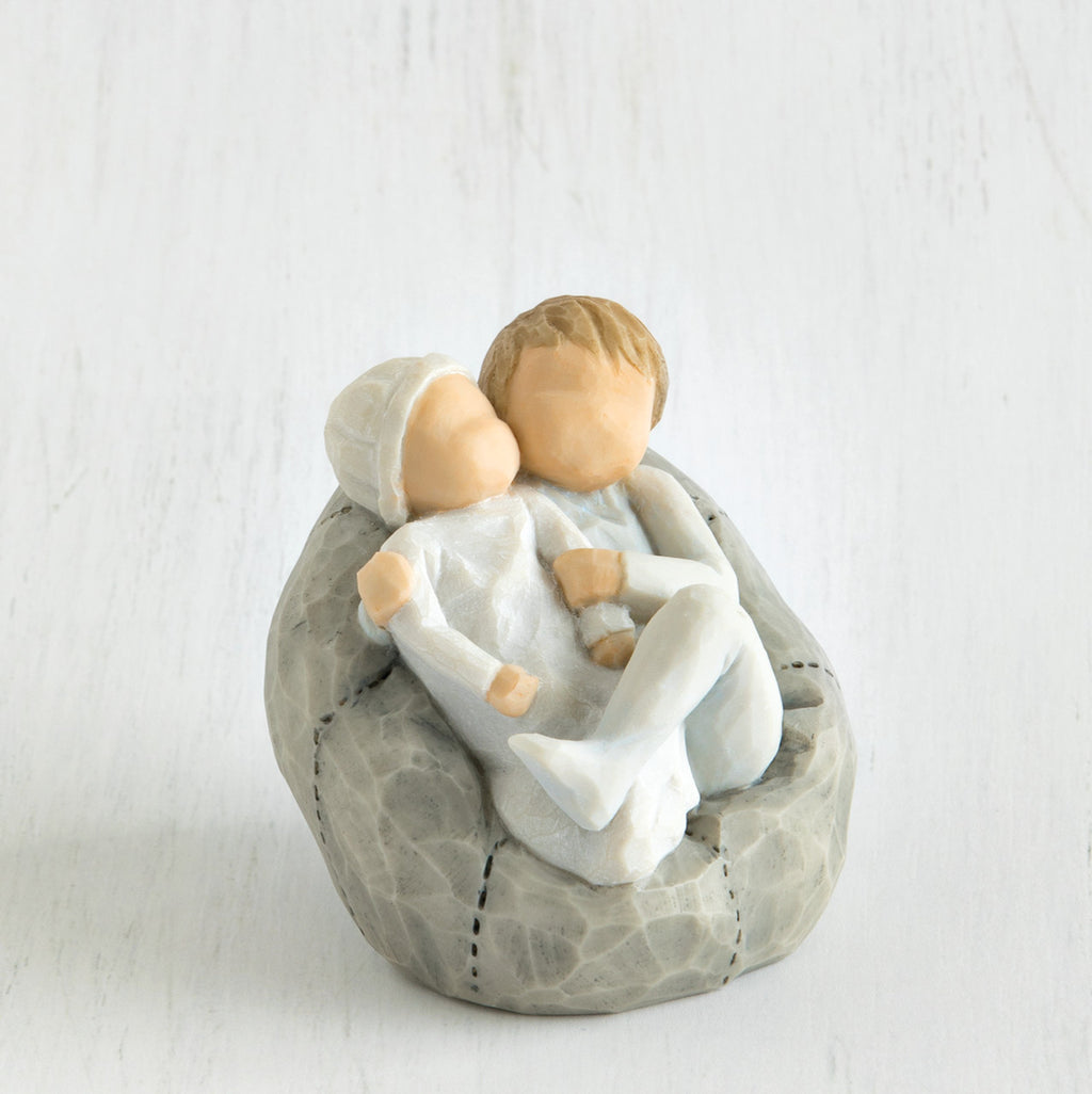 Close view of baby being held by a larger sibling on grey bean bag