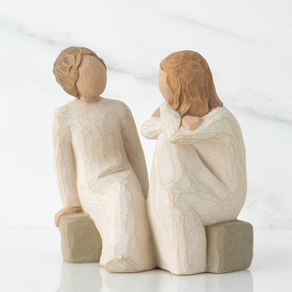 Two red haired girl figurines in white dresses sitting down on rocks