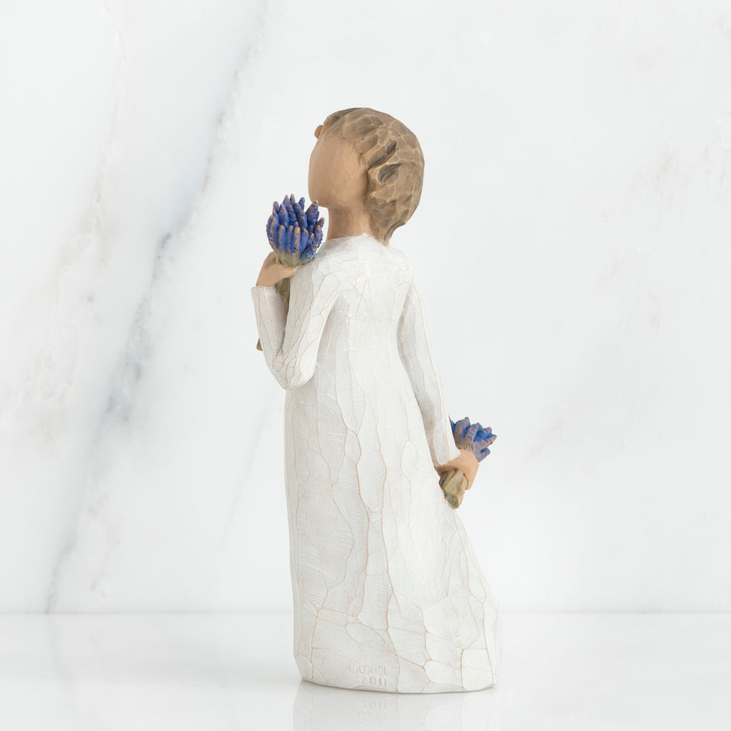 Brunette girl figurine in white dress holding blue flowers