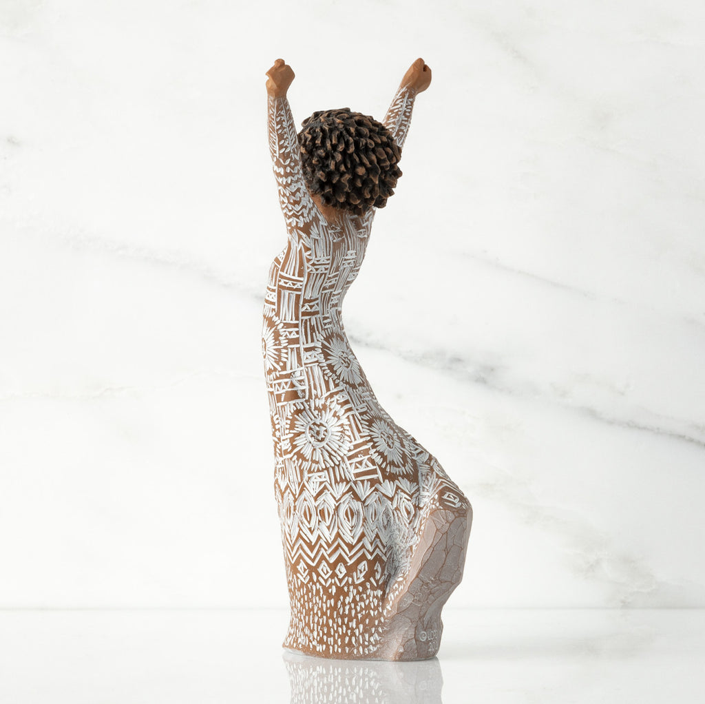 Left back of figure, with arms raised overhead, dress etched with African textile patterns