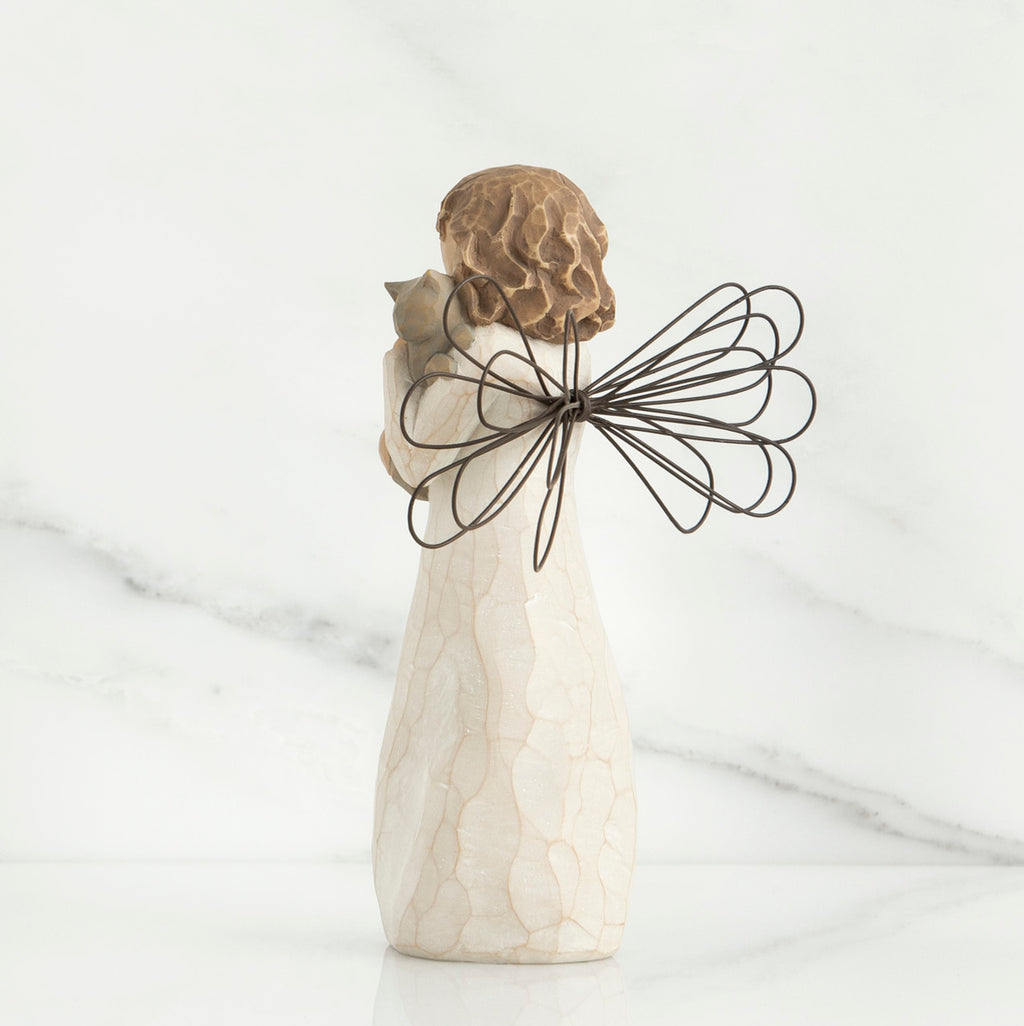 Back view of brunette angel figurine in white dress holding grey cat
