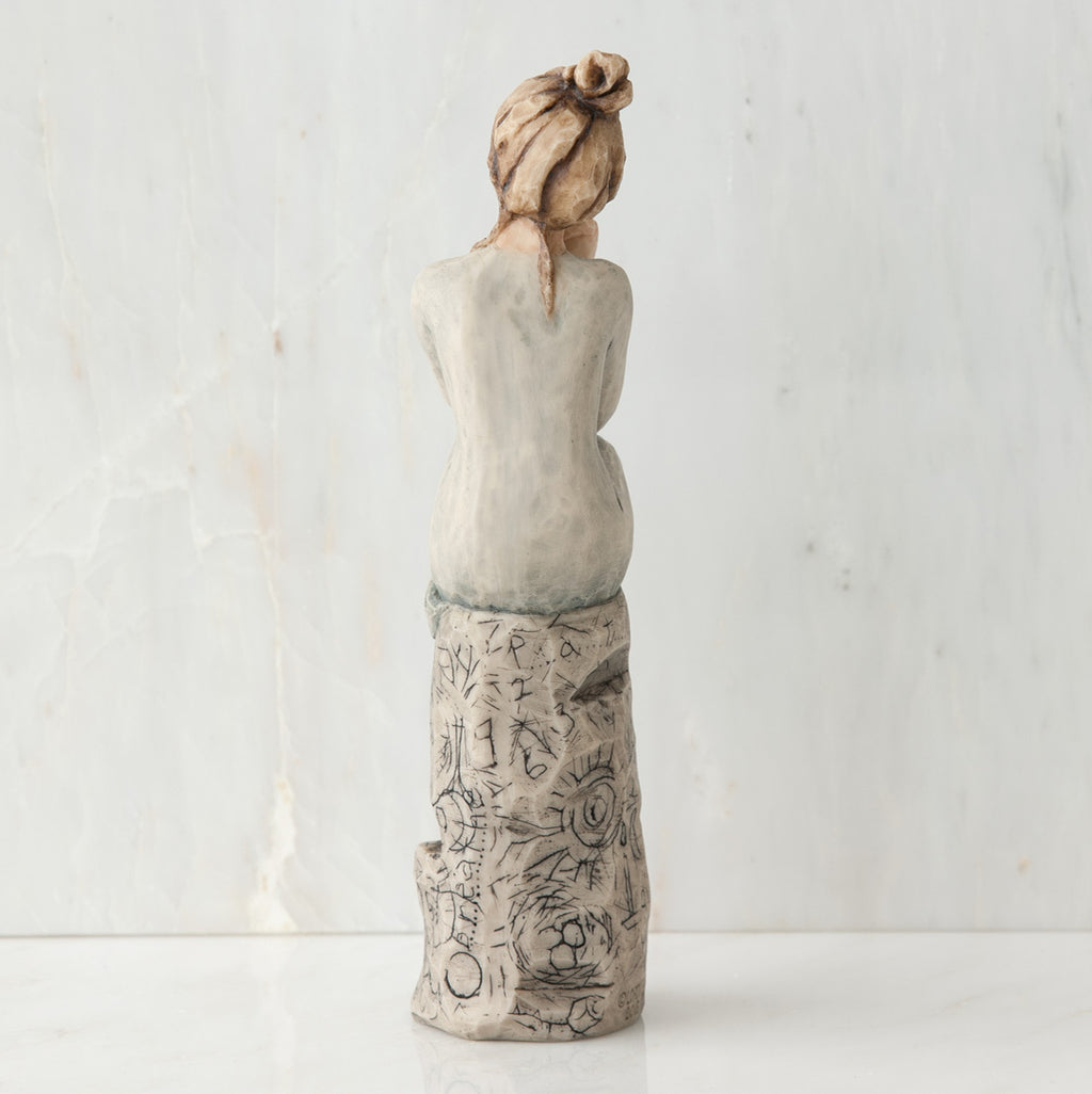 Back view of brunette girl sitting on grey rock