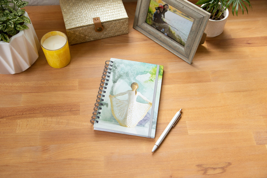Willow Tree Butterfly Notebook, 6.5"w x 8.5"h, hard-cover, spiral-bound, 240 lined pages, front cover features Butterfly figure on background of blue-green painting, closed on desk