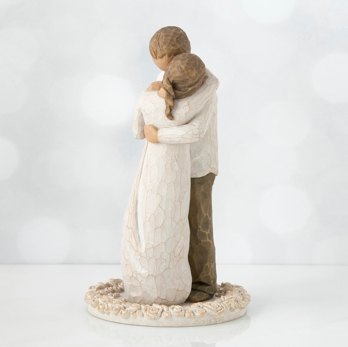 Man and woman figurine hugging one another on round cream plaque