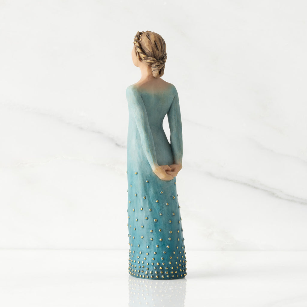 Facing left/back view: Lighter-skin figure, arms clasped behind back, hair and deep blue ombré garment dotted with gold leaf