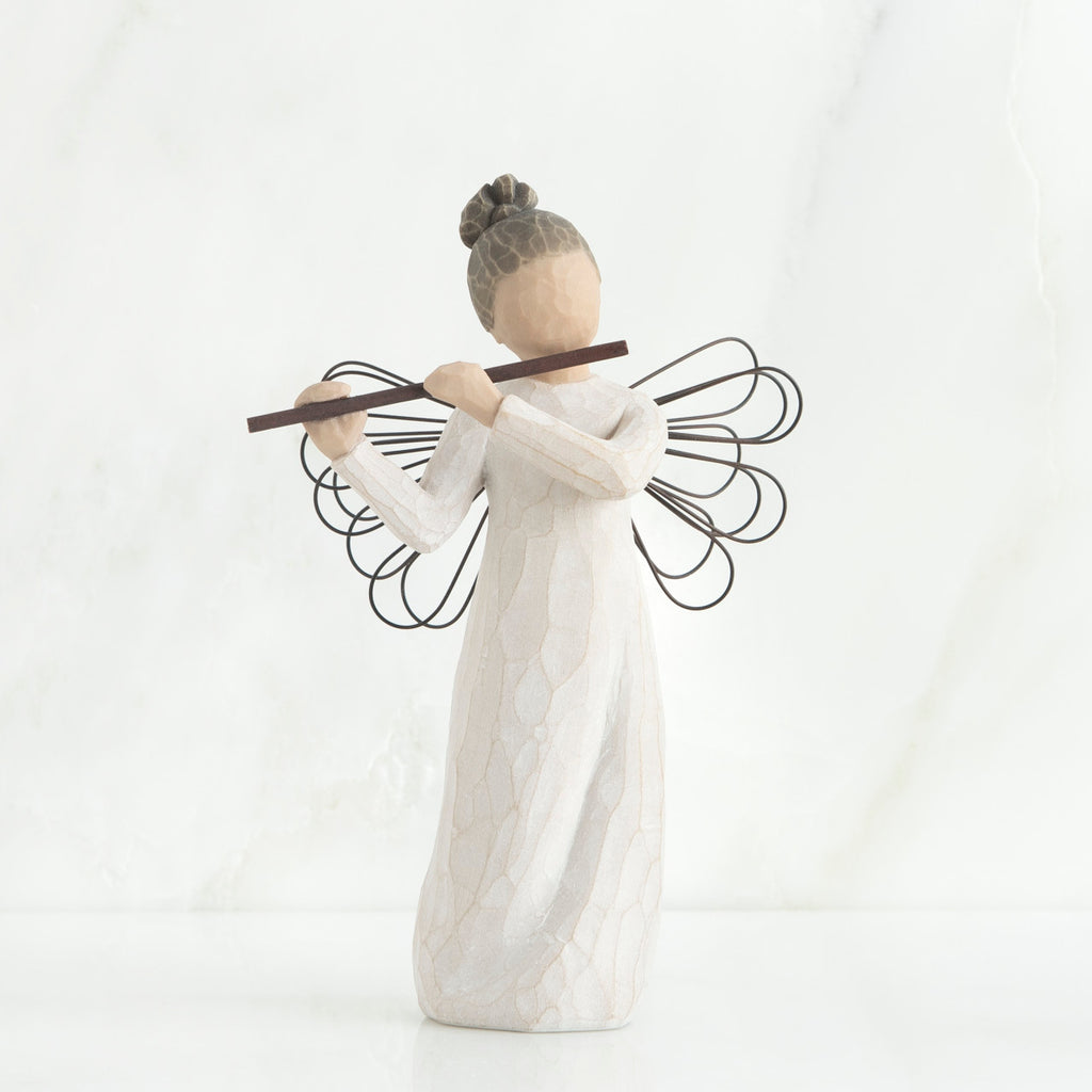 Faceless angel figurine wearing white dress and black wire wings playing black flute