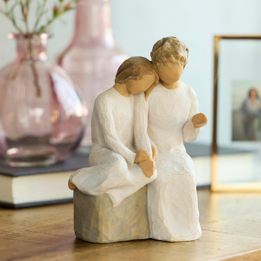 Willow Tree With my Grandmother, 5.5" hand-painted resin figure of older woman seated on gray bench, holding hands with young girl, both in cream dresses, on table with vase