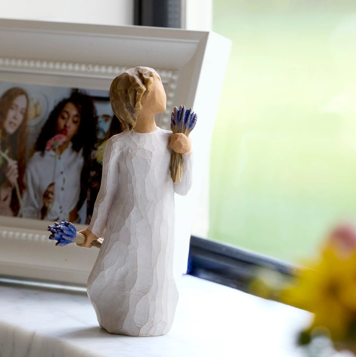 Willow Tree Lavender Grace, 5.5”h hand-painted standing resin figure in cream dress, holding two bundles of lavender flowers - one in raised hand, one at her side, on windowsill