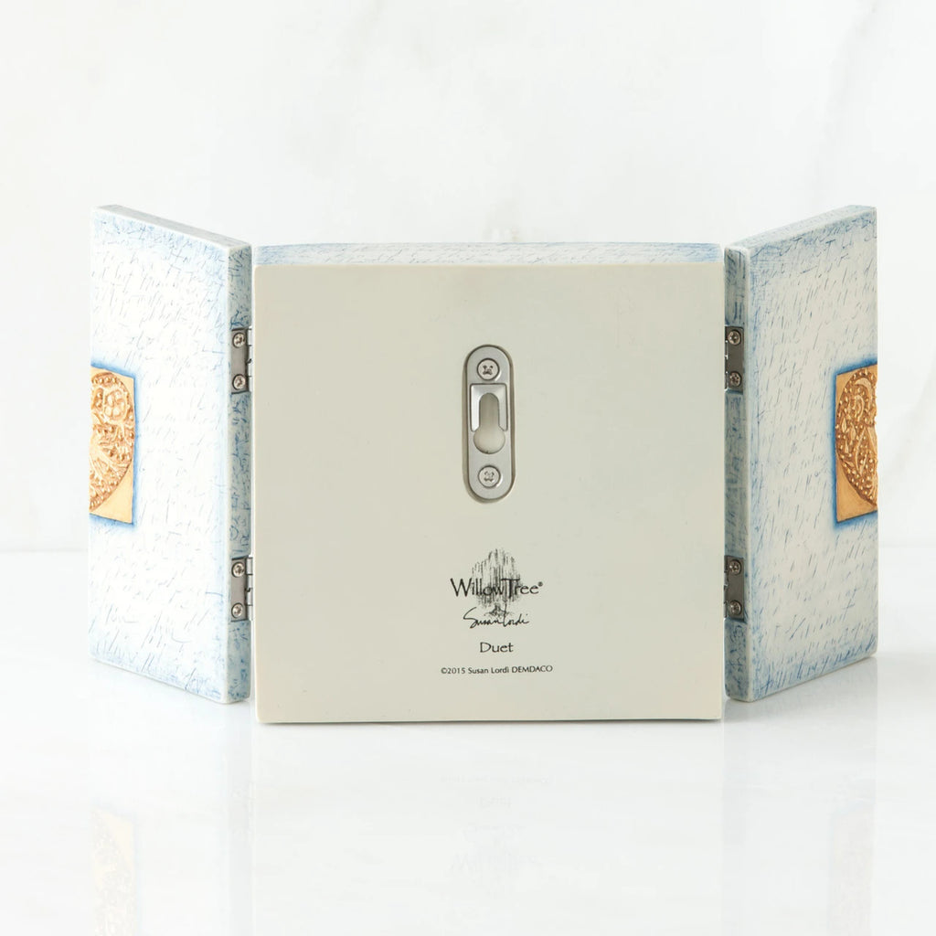 Back side of wooden white/blue book with silver key hole showing and willow tree printed in black