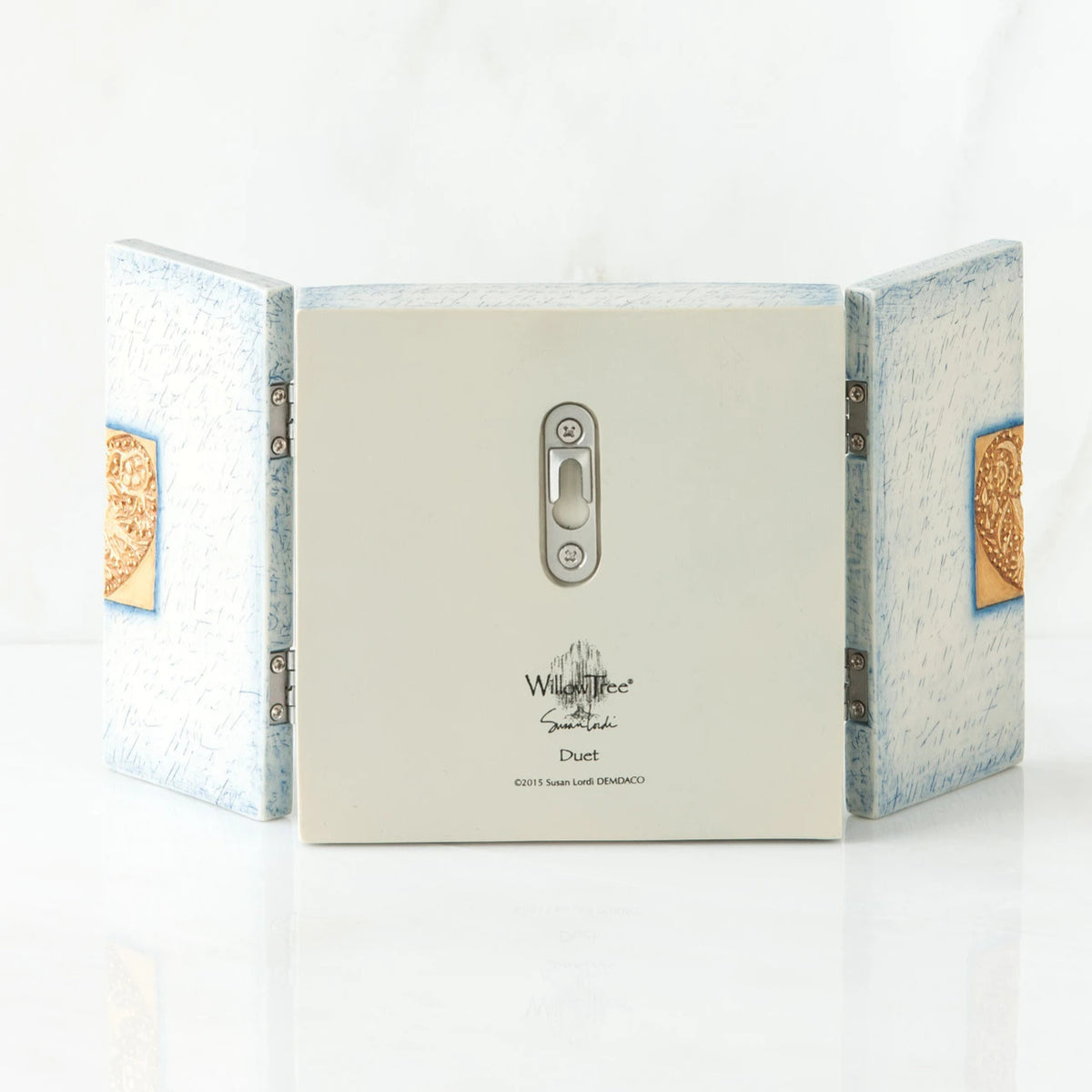 Back side of wooden white/blue book with silver key hole showing and willow tree printed in black