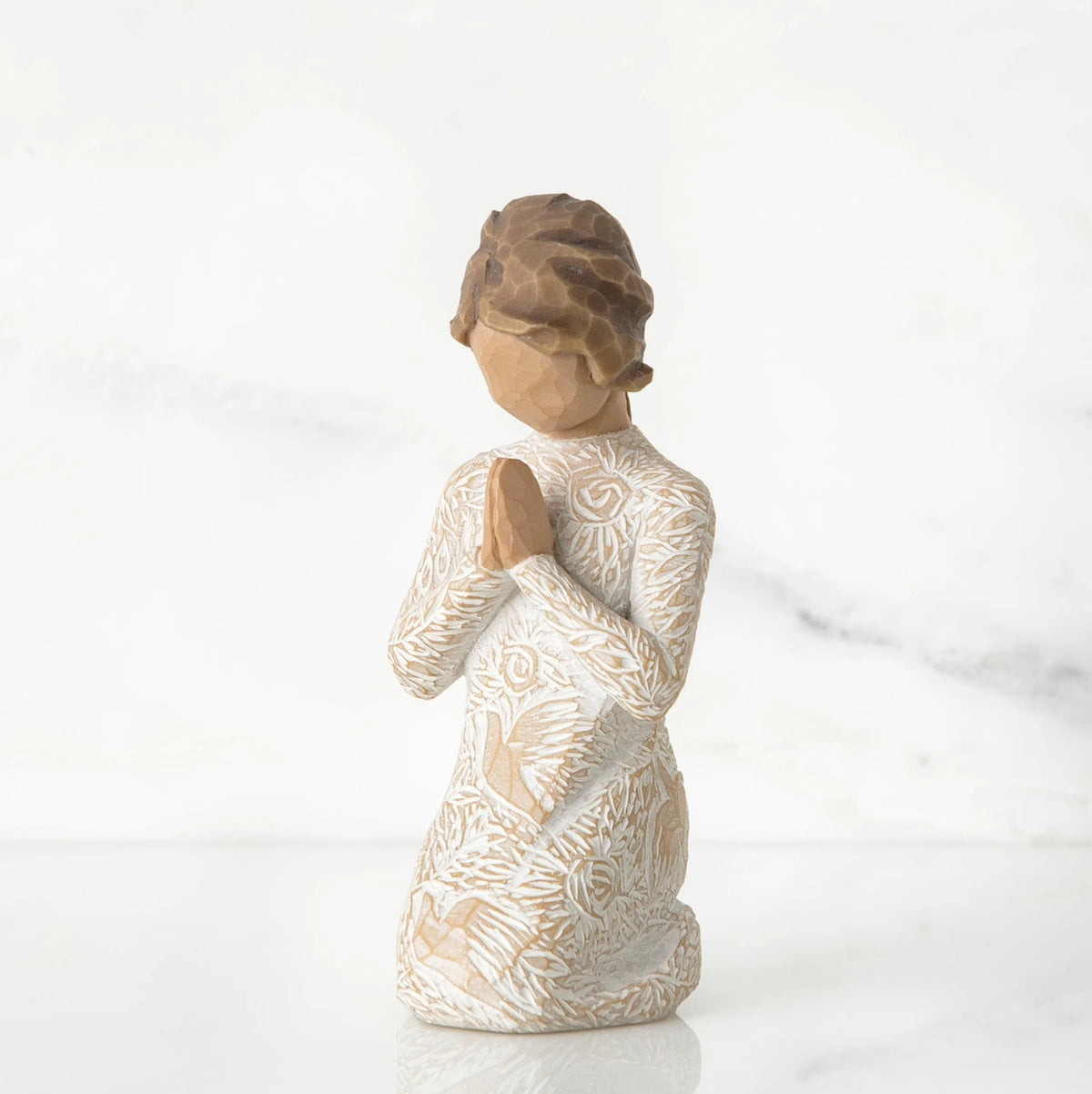 Small faceless girl figurine wearing white/tan bird design dress, kneeling and praying